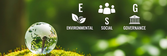 A glass globe rests on a bed of moss, symbolizing the Earth. Overlaid are icons representing ESG (Environmental, Social, and Governance) factors, highlighting sustainable and responsible business practices.